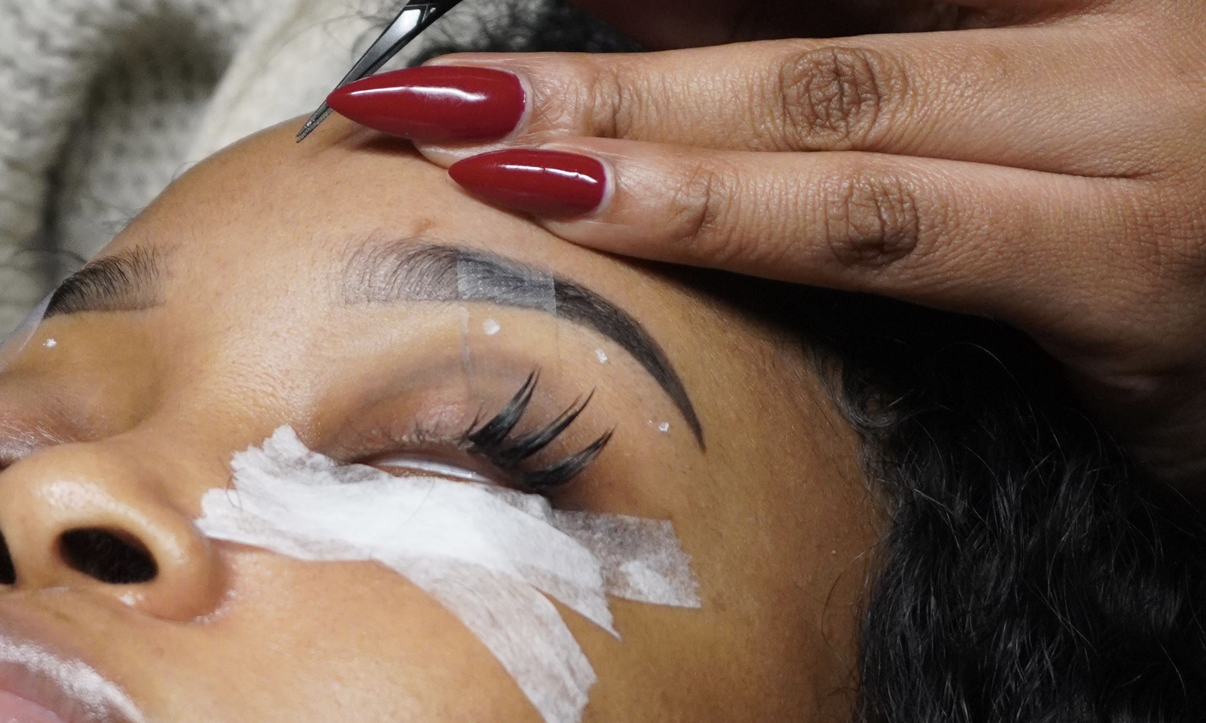 Macro of a lash extension being isolated with tweezers during application